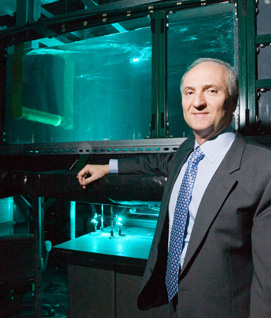 Michael Bernitsas, professor in the Department of Naval Architecture and Marine Engineering, stands before a prototype of his VIVACE hydrokinetic energy device. (Photo: Scott Galvin)