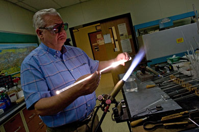 U-M scientific glassblower Harald Eberhart heats a tube of quartz to 2,000 degrees C. Eberhart, who has been blowing glass since age 14, can make complex, one-of-a-kind scientific instruments to order, saving the university time and money and creating new research possibilities for its scientists. (Photo: Martin Vloet, U-M Photo Services.)