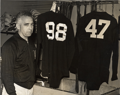 Henry Hatch, U-M's famed equipment manager, with two of the jerseys he retired: Tom Harmon (98) and Bennie Oosterbaan. (Photo courtesy U-M Bentley Historical Library.)
