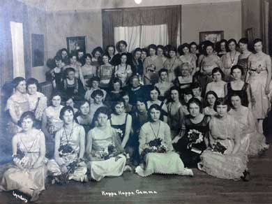 A black and white photo of about one hundred women in formal dress posing for a photo of their sorority.