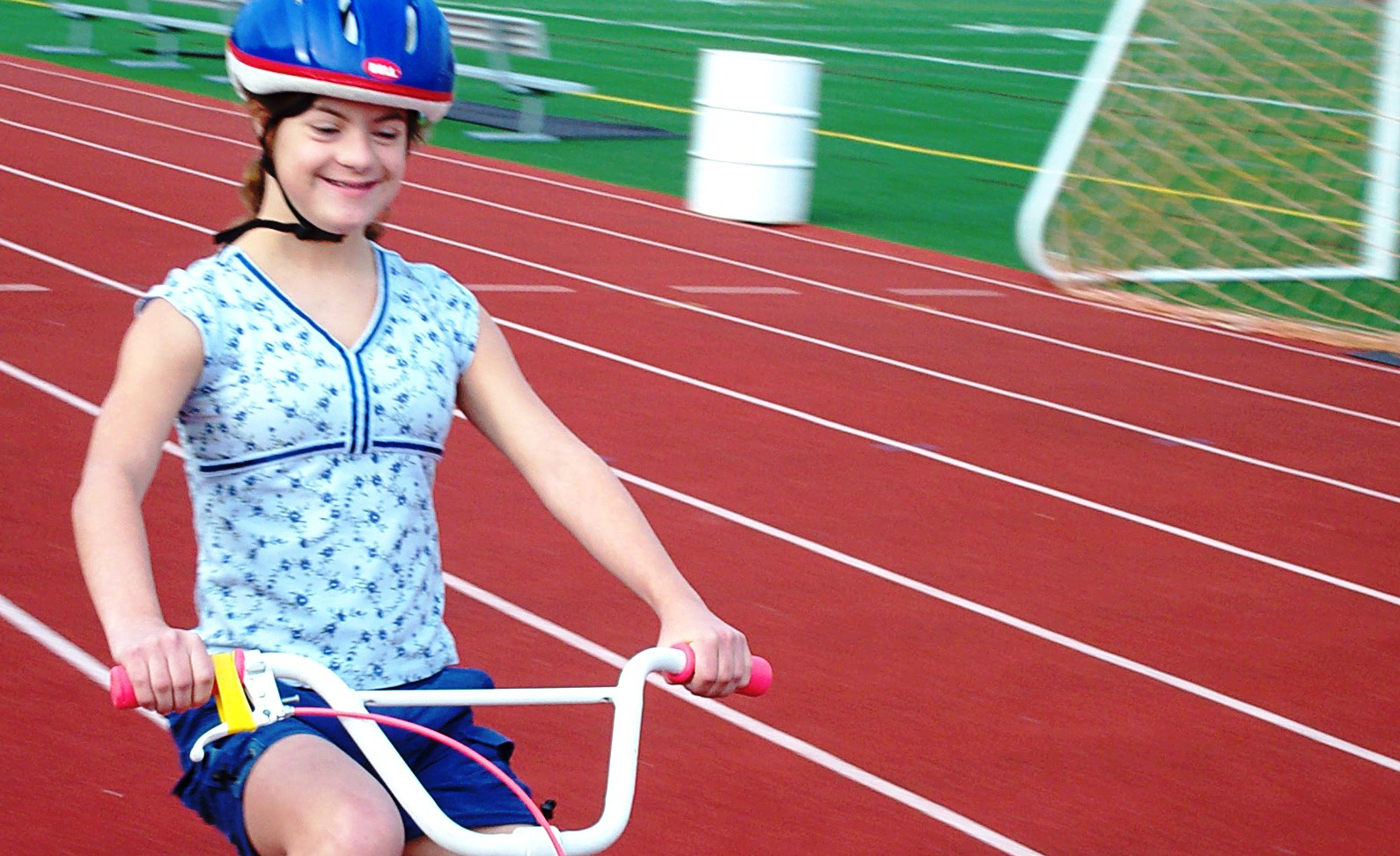 University of Michigan School of Kinesiology bike camp participant Bridget Richards zooms around happily on her two-wheel bike. Richards was part of the 'bike camp' study conducted by U-M Kinesiology. The study looked at the feasibility and benefit of teaching children with Down syndrome to ride two-wheel bikes. U-M Kinesiology teamed with the nonprofit group Lose the Training Wheels, which provided the specially designed bikes and the individualized training. The majority of participants learned to ride after five consecutive days of 75 minute individualized training sessions. Photo courtesy of Greg and Mary Anne Richards