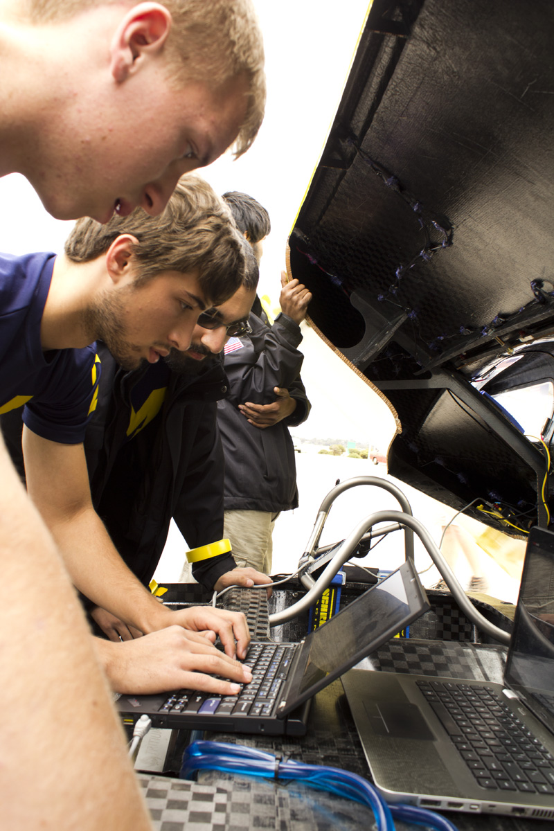 University of Michigan solar car team race crew members Santosh Kumar, Aeresh Bilmoria, Jordan Feight and AJ Trublowski check under the hood during a control stop on a practice race in Australia. Credit: Evan Dougherty