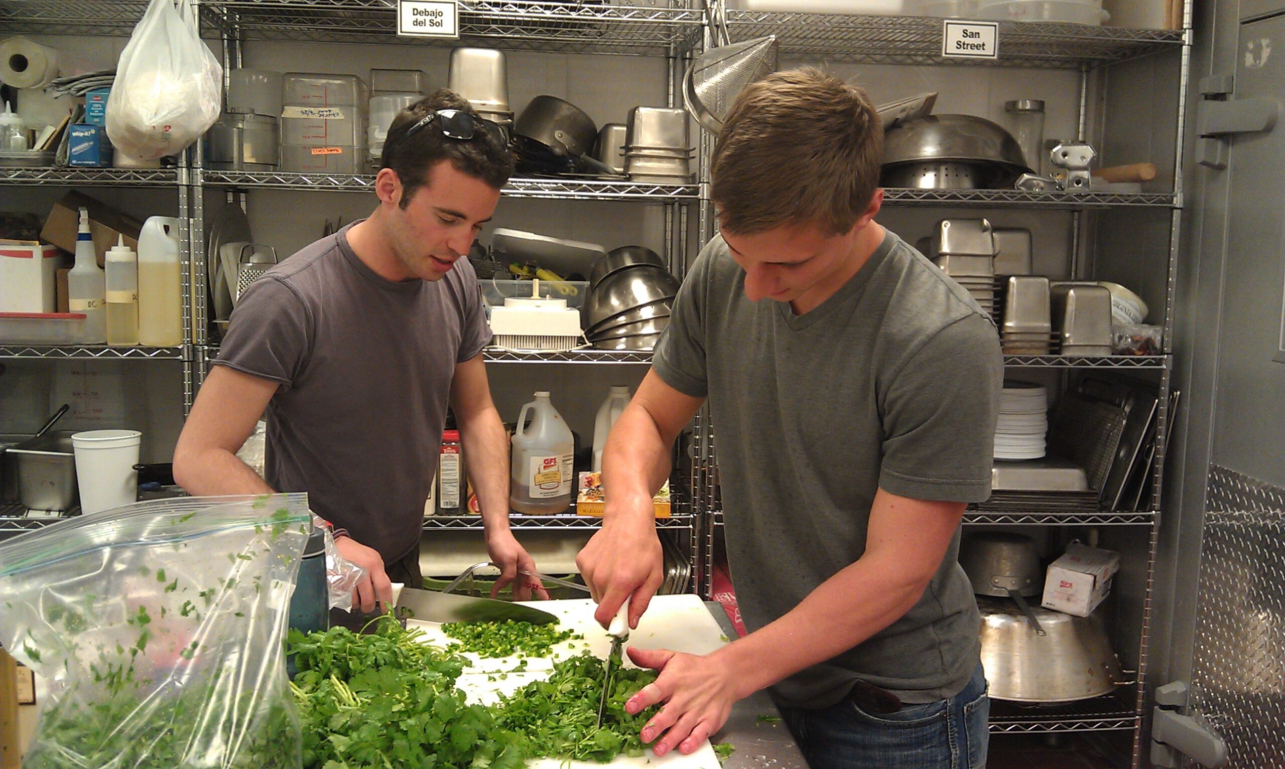 The Beet Box's Alex Perlman and Colton Babladelis (a student in the College of Literature, Science and the Arts, chop cilantro on Thursday night in preparation for opening day. Photo courtesy of the Beet Box 