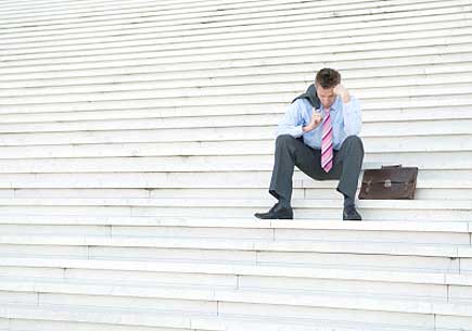 Businessman hangs his head on a set of bleak white steps