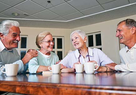 Two senior couples drinking coffee together in community center. (stock image)