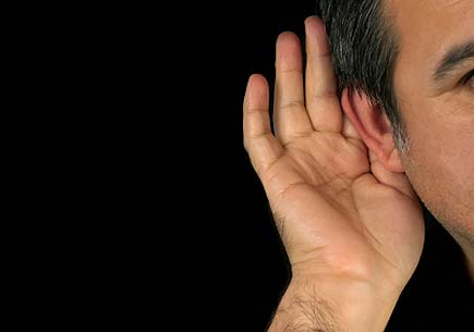 Photo of a man holding his hand to his ear (stock image)