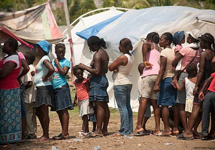 Port-au-Prince, Haiti, March 16, 2010: Food distribution in a refugee camp. The people line up patiently to get food and water. (stock image)