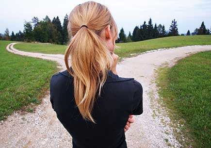 A woman the crossroad at some rural hilly road. (stock image)