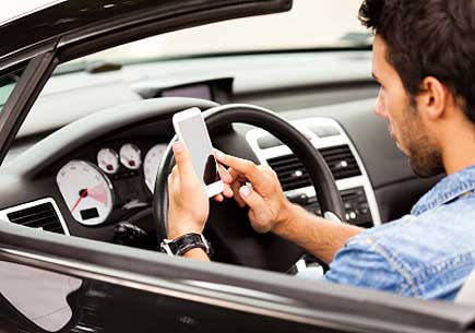 Close up of a young man using smart phone in his car. (stock image)