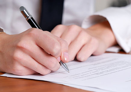 Person's hand signing an important document (stock image)