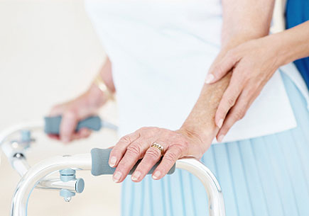 A close-up of a young woman's hands and an old lady's hands using a walker as support. (stock image)
