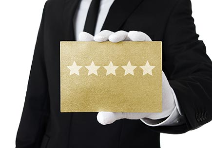 Human hand holding gold card with five stars on it. (stock image)