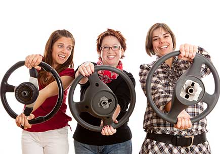 Three women holding steering wheels. (stock image)