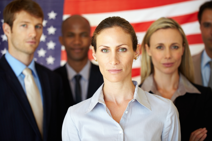 Portrait of several men and women standing with flag in the background (stock image)