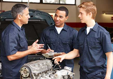 Mechanic training apprentices in workshop (stock image)