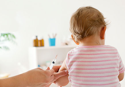 Back view of baby girl patient receiving vaccine at the doctor's office. (stock image)