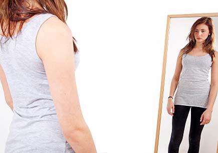 A teenage girl looking at mirror with diffidence feeling (stock image)