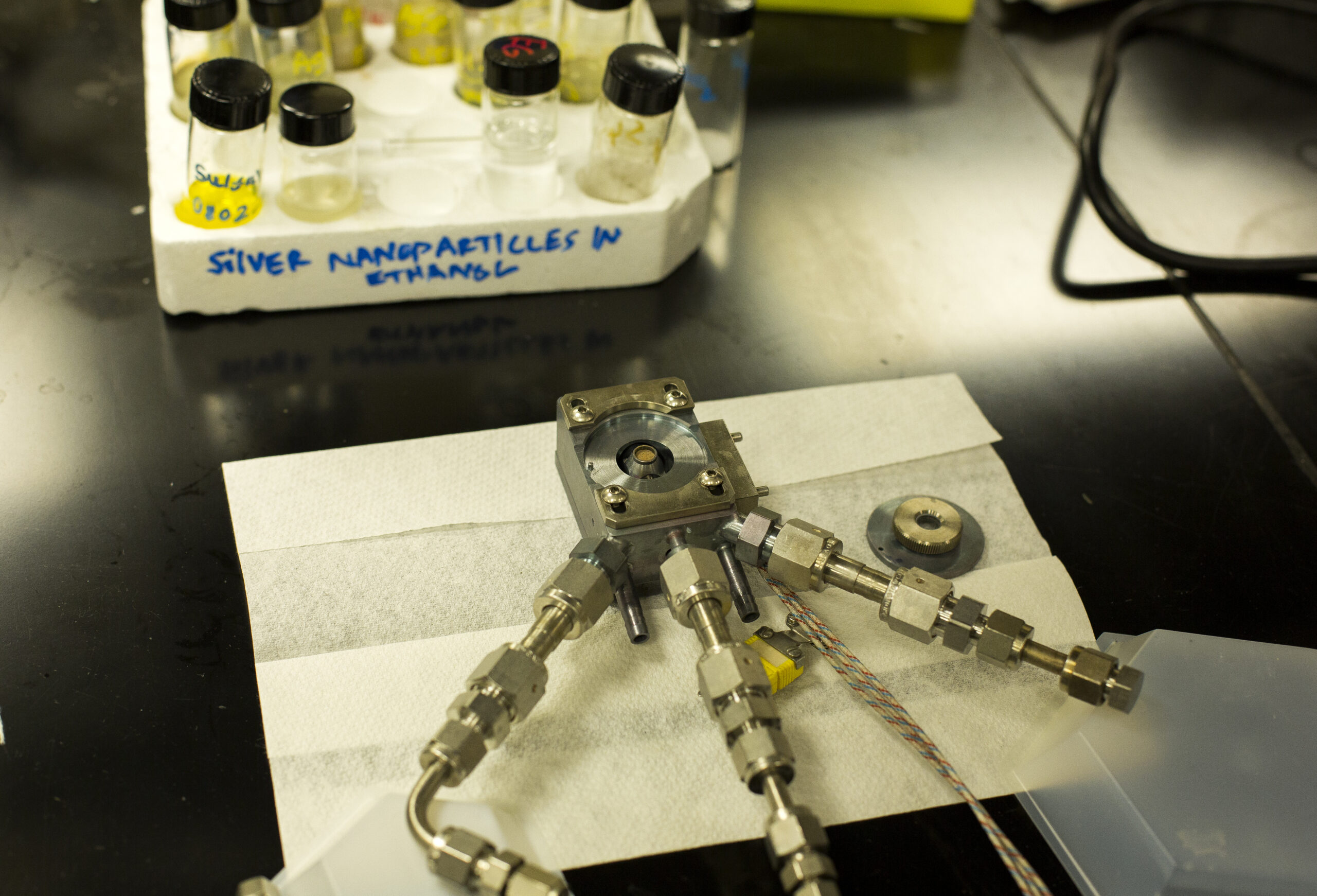 The test reactor holds the catalyst in a tiny circular bed and exposes it to propylene and oxygen gasses. When the reactor is closed, a light shines down from the top, allowing the copper to keep the oxygen from binding to its surface. The copper can instead bind the propylene to the oxygen, forming the industrially important chemical propylene oxide. Photo: Joseph Xu, Michigan Engineering Communications & Marketing.