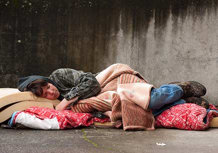 Homeless woman lying on the street. (stock image)