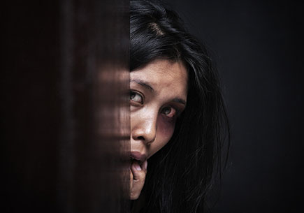Abused woman hiding in dark, concept for domestic violence (stock image)