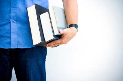 Cropped image of a male hand holding several books against his hip. (stock image)