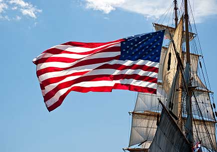 Old historic wooden tall ship flies the American flag off its stern. (stock image)