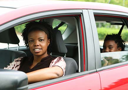 A woman driving with her child in the back seat. (stock image)