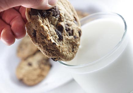 Dipping a cookie into a glass of milk. (stock image)