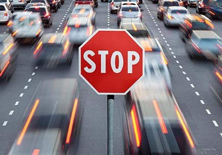 A stop sign superimposed over motion blurred cars on a highway. (stock image)