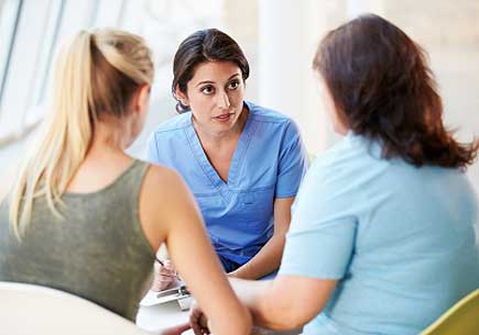 A nurse talks with two women. (stock image)