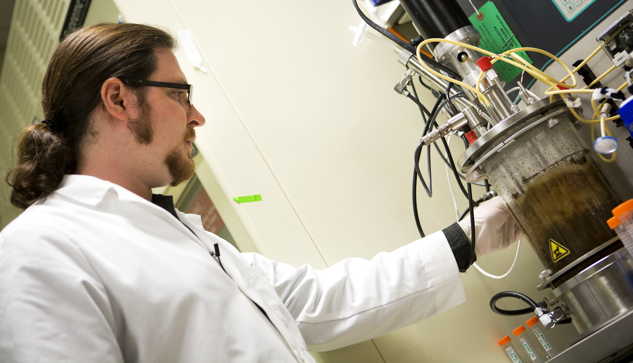 Jeremy Minty, a recent doctoral graduate in Nina Lin's lab at U-M, adjusts the bioreactor in which the fungus and bacteria convert tough plant materials to biofuel. Image credit: Joseph Xu
