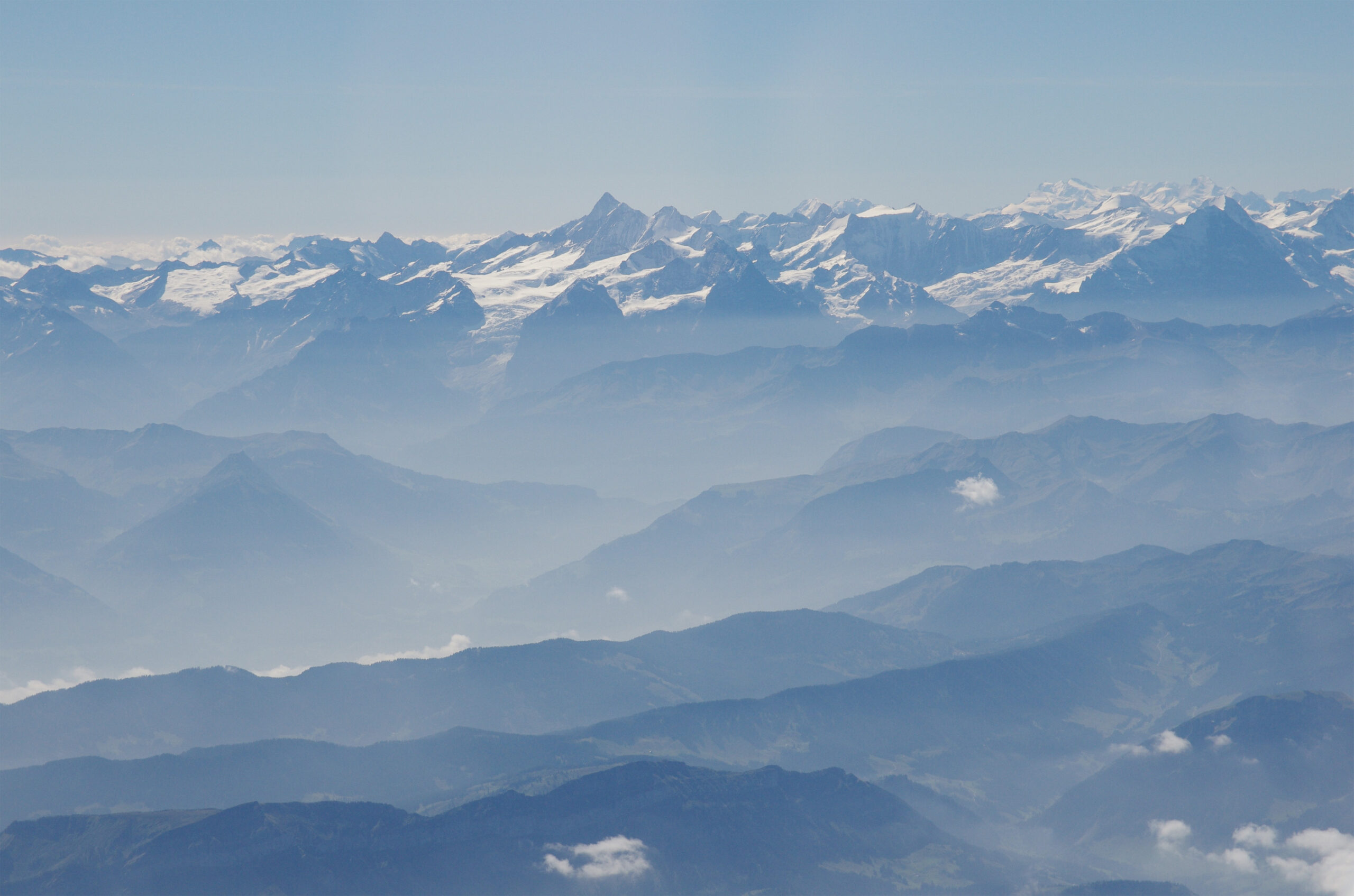 This photo from summer 2012 shows how air pollution in the Alps tends to be confined to lower altitudes, concentrating the deposition of soot and dust on the lower slopes. At center left in this picture, a glacier can be seen extending from a high altitude snow field, above the pollution layer, down into the valley where its lower reach is bathed in pollutants. Image credit: Peter Holy