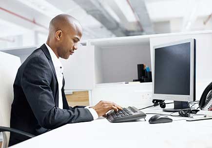 A young man in a suit hard at work in a sparse office. (stock image)