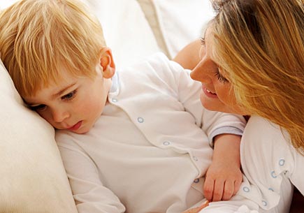 A mother leans in toward her young son, while he looks away. (stock image)