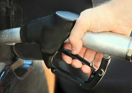 A hand holding a gasoline nozzle fills up a gas tank. (stock image)