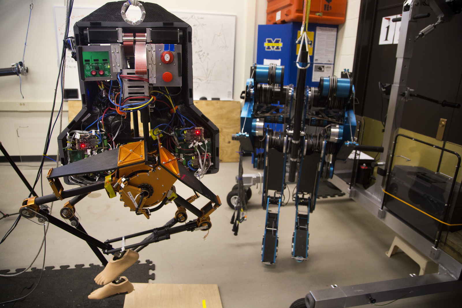 MARLO, a bipedal robot, next to its predecessor, MABEL, in a lab located in the Environmental and Water Resources Engineering Building on November 19, 2013.  MARLO is the successor in EECS Professor Jessy W. Grizzle's research group to MABEL, another bipedal robot that is being retired to be displayed in the Chicago Field Museum.  Buss and members of Grizzle's research group test the robot, making minute adjustments to improve its ability to walk in hopes of having applications in human prosthetics and the general robotics community. Image credit: Joseph Xu, Michigan Engineering Communications & Marketing