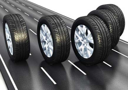 Digital rendering of five tires rolling on a strip of road. (stock image)