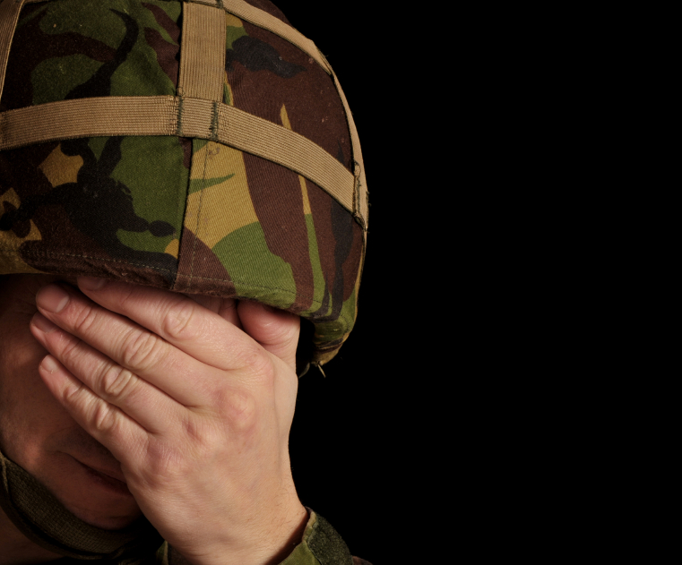 A soldier covers his face with his hands. (stock image)