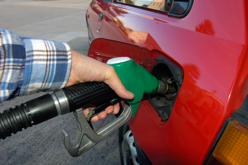A hand on a gas pump filling up a car's gas tank. (stock image)