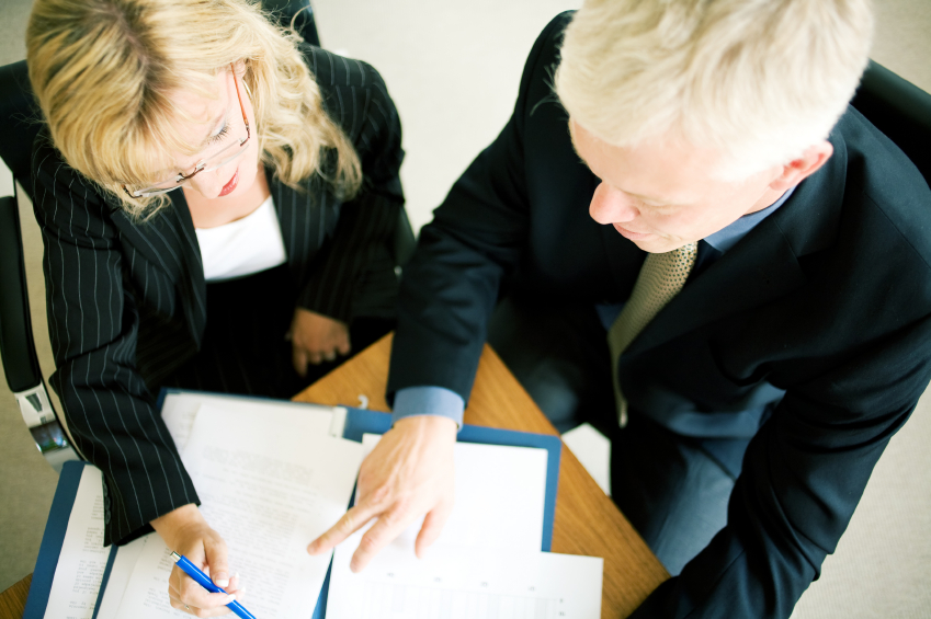 Overhead view of two business professionals examining documents. (stock image)