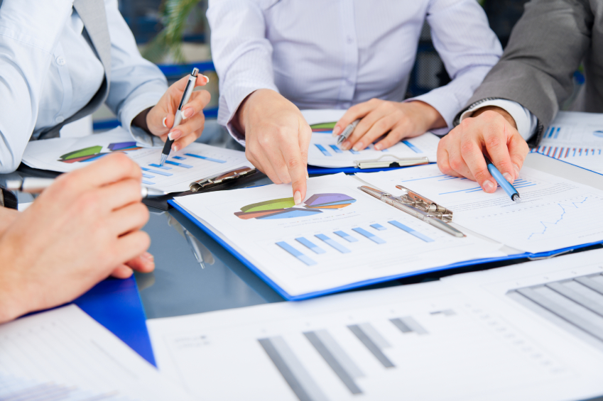 A cropped group of business professionals analyzes data. (stock image)