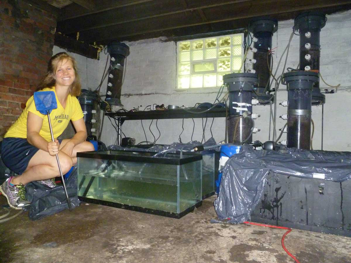  Lizzie Grobbel with the equipment used to grow shrimp in the basement of an unoccupied Detroit home. Image credit: Lizzie Grobbel