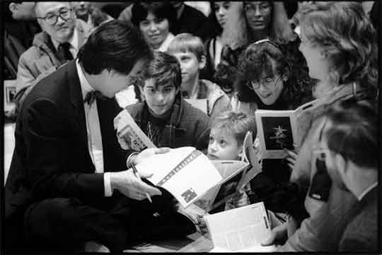 Cellist Yo-Yo Ma sits on the Hill Auditorium stage and autographs concert programs for youth from the Saline schools after his January 10, 1991, concert.