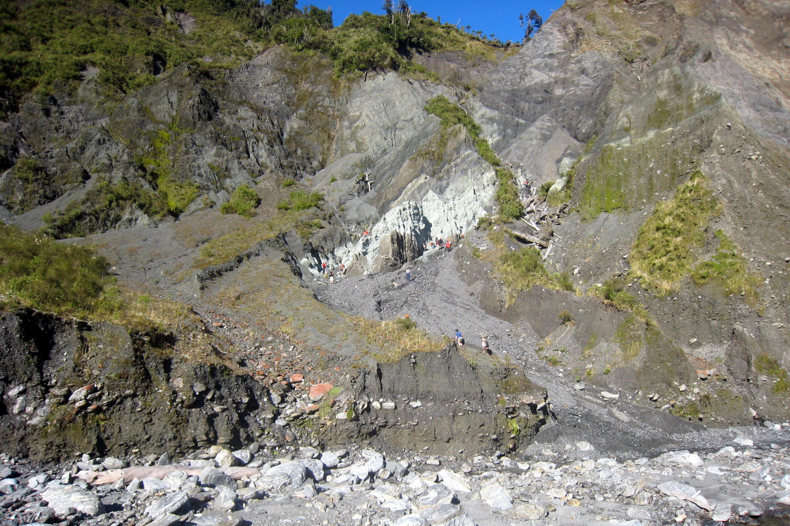 The white rocks in the center of the photo are a surface outcrop of the Alpine Fault. The Pacific tectonic plate is to the left and above the fault, and the Australian plate is to the right and below the fault. Movement along the Alpine Fault generates large earthquakes every 200 to 400 years, with an average time between successive large earthquakes of about 330 years. The last Alpine Fault quake occurred in 1717. Image credit: Ben van der Pluijm