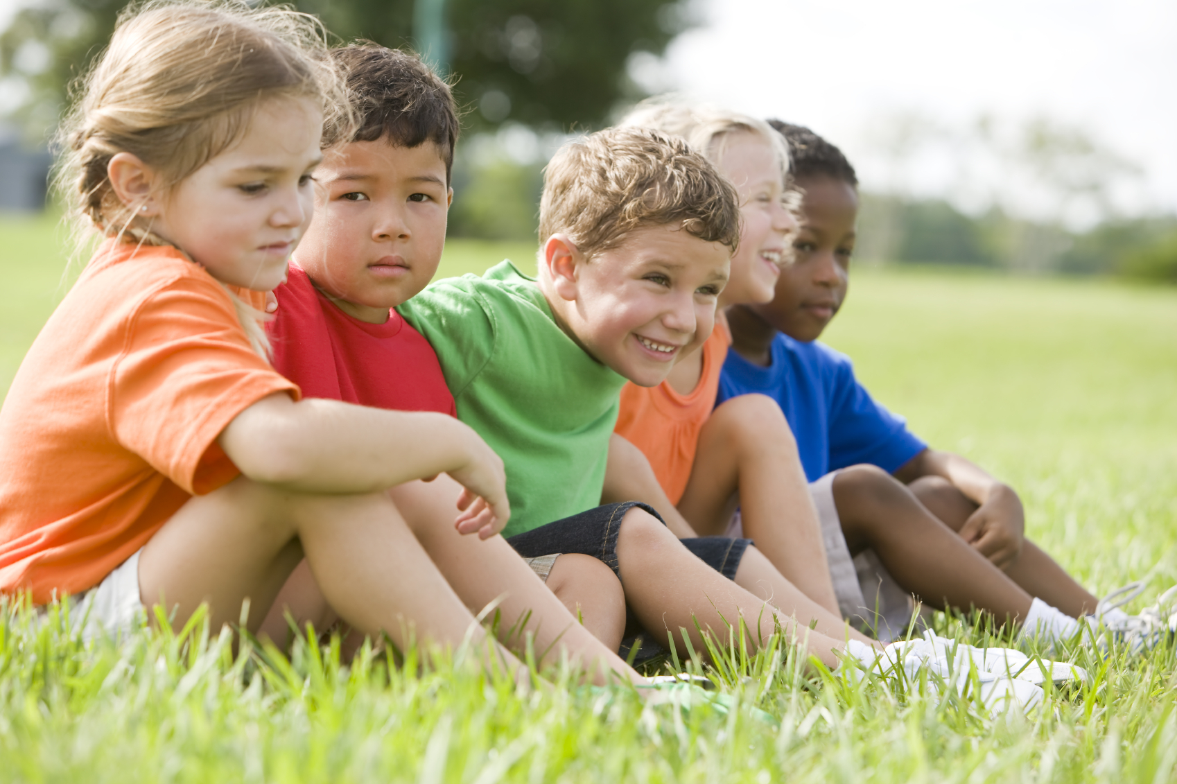 A group of preschoolers sits together outside. (stock image)