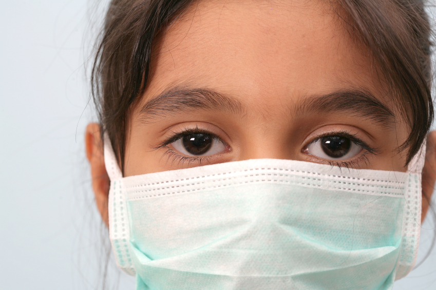 A little girl's face is obscured by a surgical mask. (stock image)