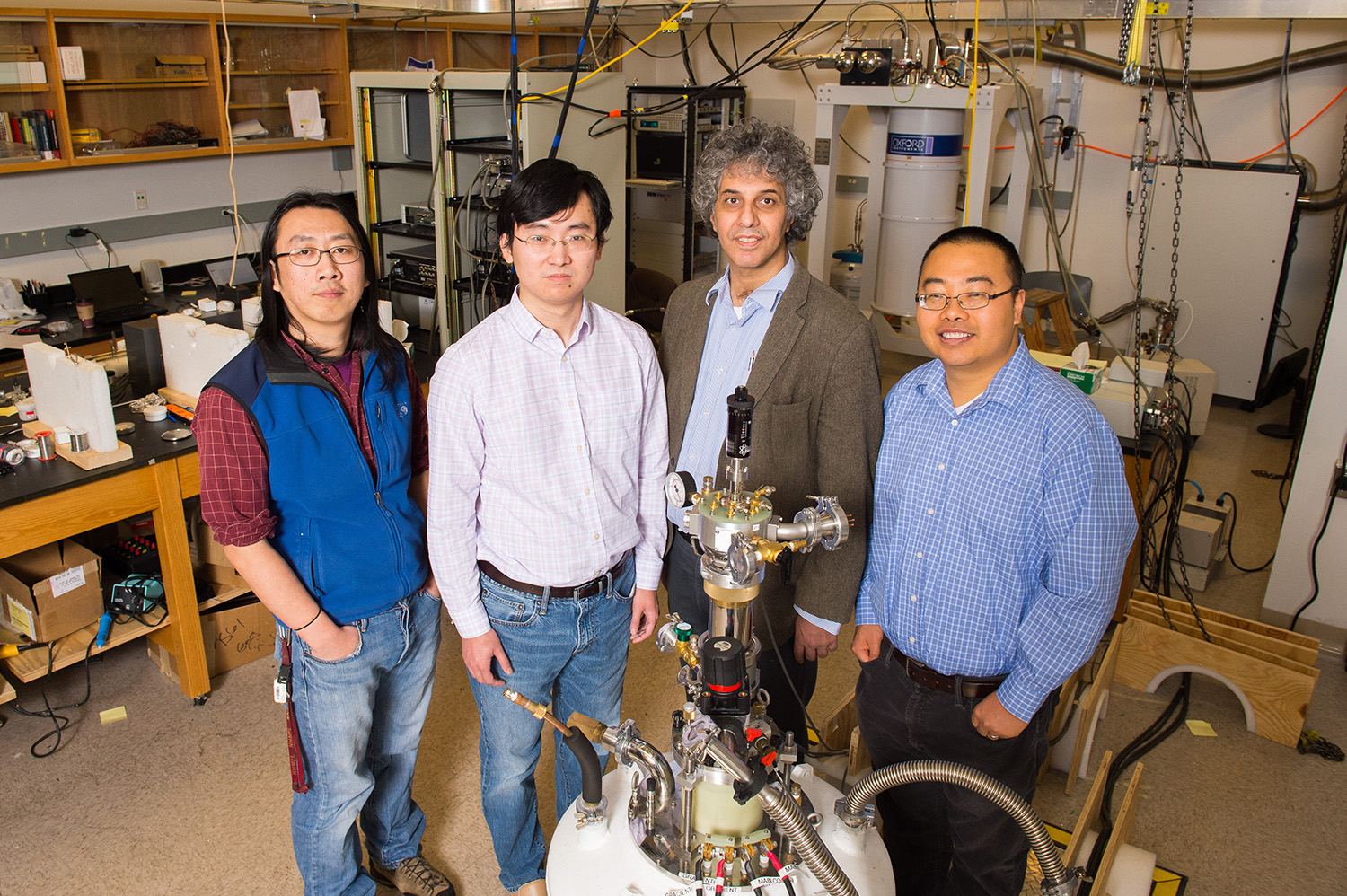 Physics researchers at the University of Michigan have confirmed the strange electrical behavior of a material called samarium hexaboride. The compound, it turns out, is a topological insulator. Gang Li, postdoctoral researcher; Kai Sun, assistant professor; Cagliyan Kurdak, professor; and Lu Li, assistant professor, stand in front of their experimental set-up. Image credit: Daryl Marshke, Michigan Photography