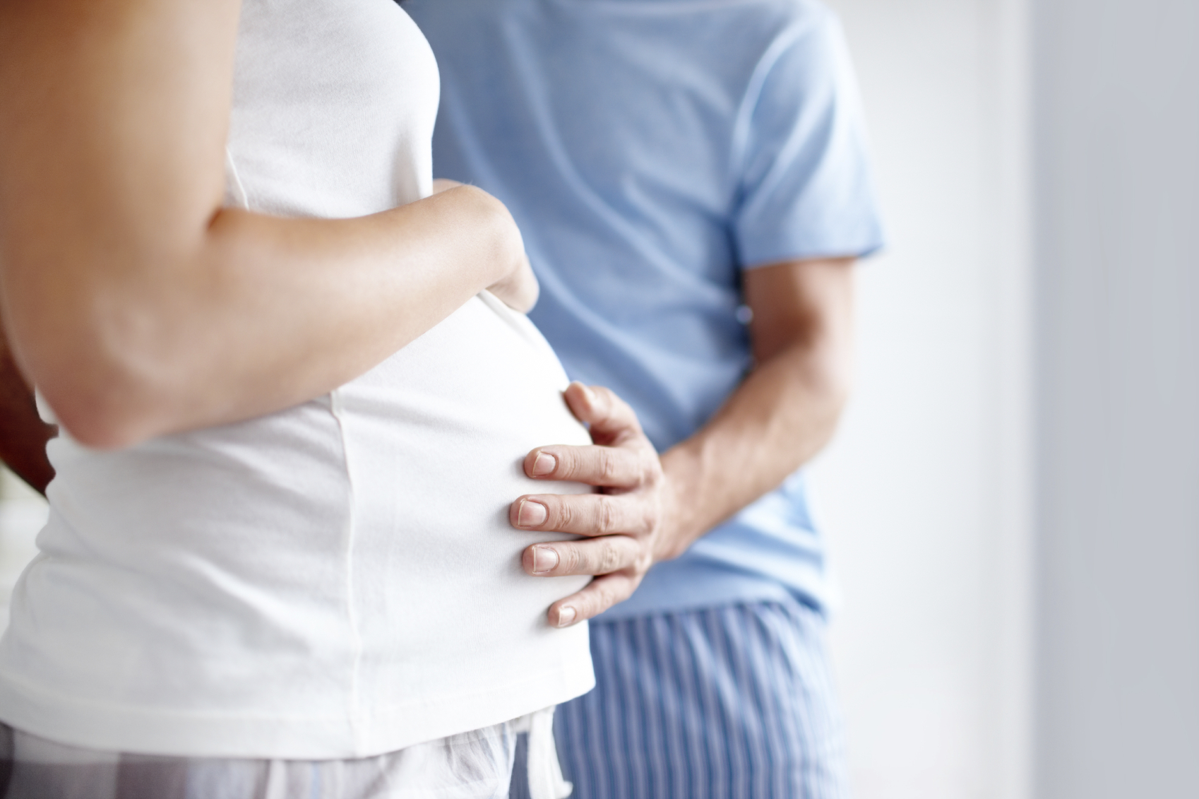 A man places his hand on a pregnant woman's belly. (stock image)