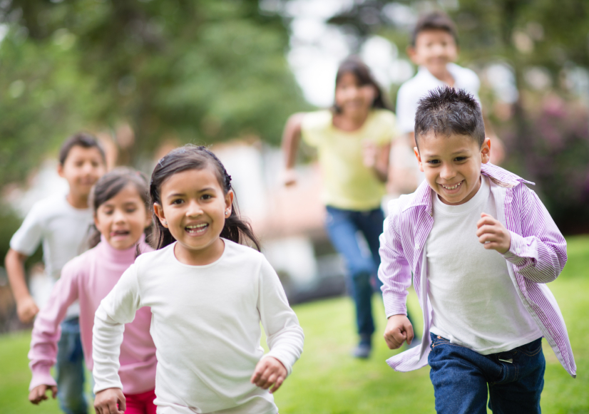 Hispanic children running in a park. (stock image)