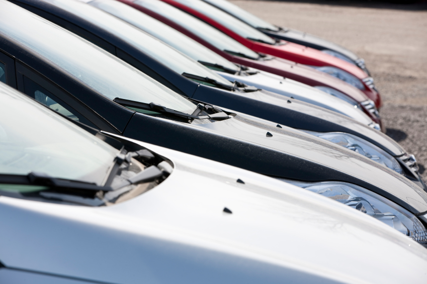 Lineup of new fuel efficient cars in dealership's parking lot. (stock image)